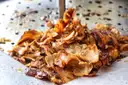 Carne de döner en tiras chisporroteando en una plancha de metal caliente
