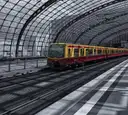 Un tren rojo y amarillo del S-Bahn bajo el techo de cristal de la estación central de Berlín