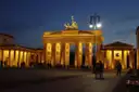 La Puerta de Brandeburgo iluminada al anochecer, con algunas personas paseando por la Pariser Platz