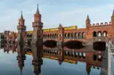 El puente Oberbaum de ladrillo rojo con un tren amarillo del U-Bahn, reflejado en el Spree en calma