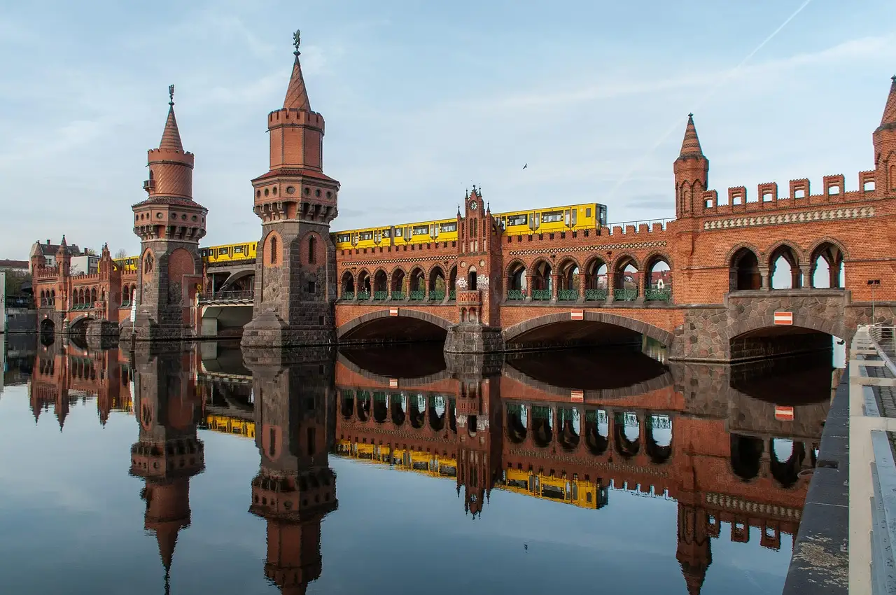 El puente Oberbaum, de ladrillo rojo, con un tren amarillo del U-Bahn reflejado en las aguas tranquilas del Spree