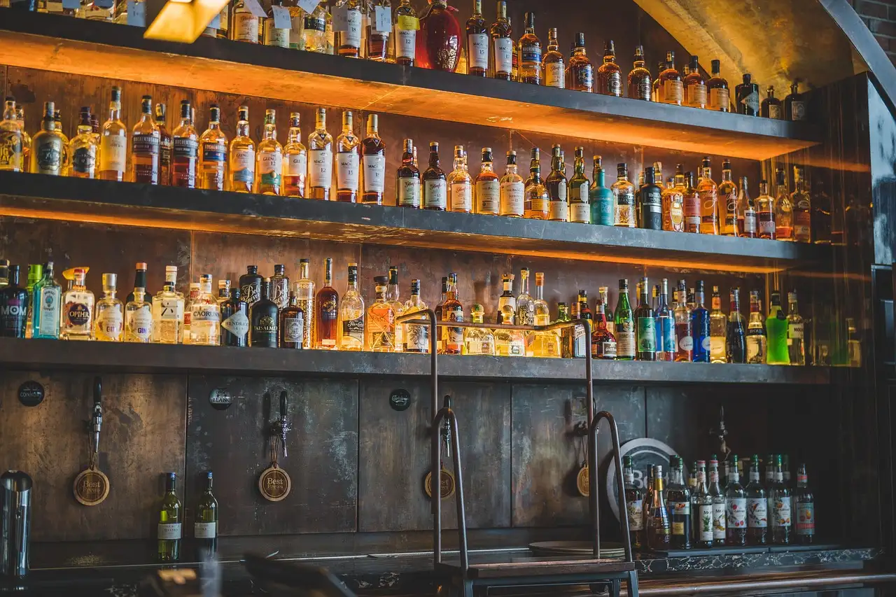 Un bar en penumbra con estanterías retroiluminadas llenas de botellas