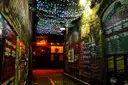 Un estrecho callejón entre patios de Berlín de noche, con guirnaldas de luces de colores y carteles en las paredes de ladrillo