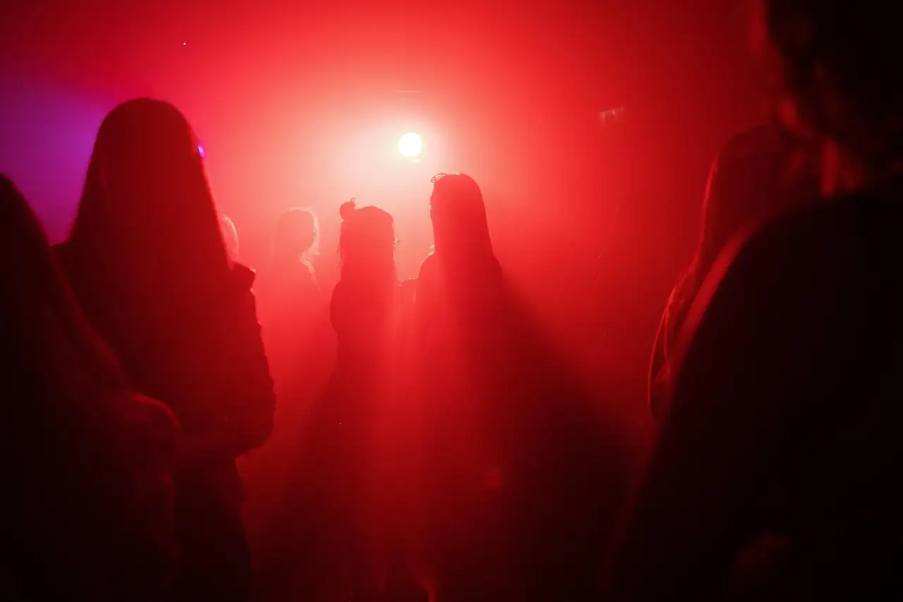 Gente bailando en un club bajo una luz roja, vista de espaldas