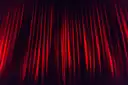 Un telón rojo de escenario iluminado desde arriba