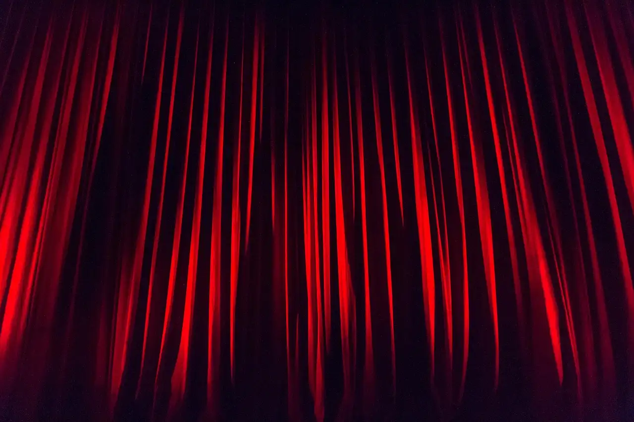 Un telón rojo de escenario iluminado desde arriba