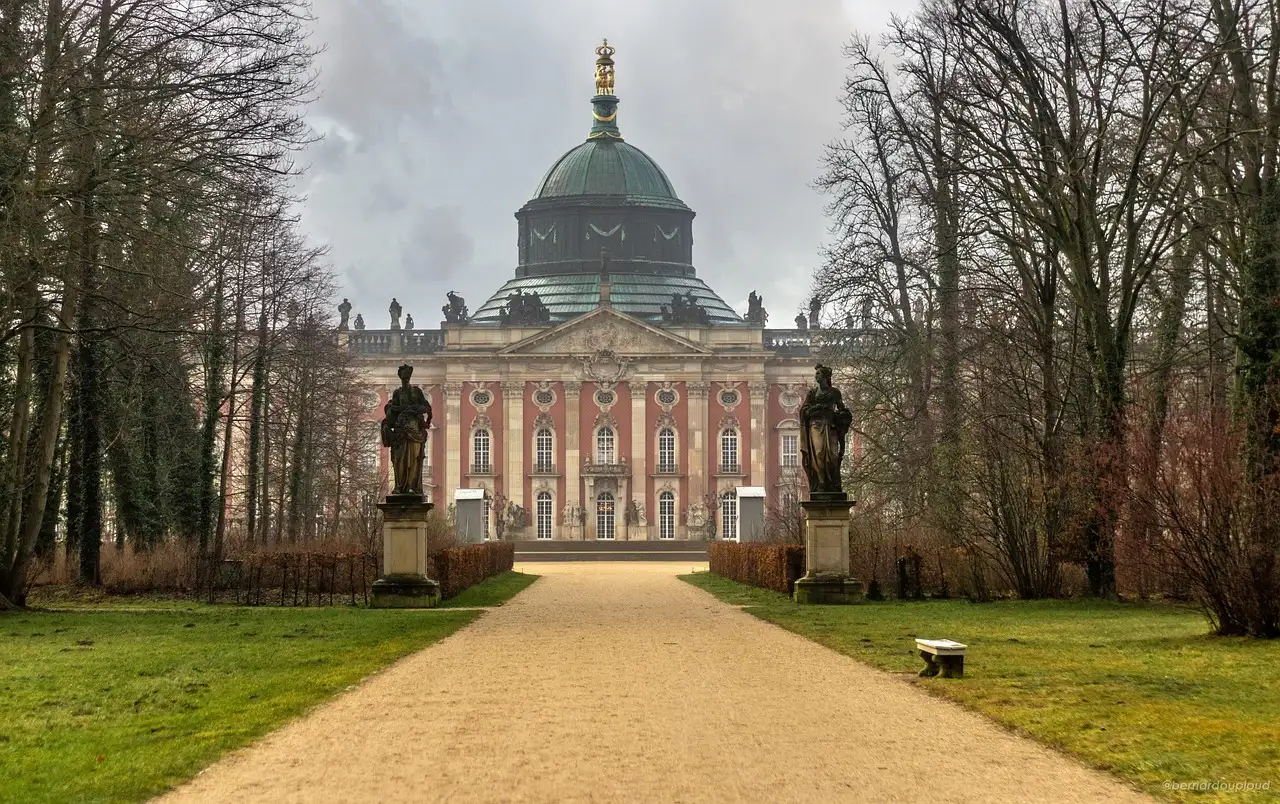 El Palacio Nuevo de Potsdam al final de una avenida con árboles y estatuas