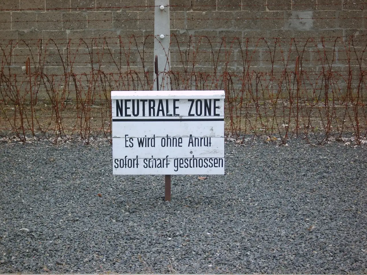 Un cartel de aviso de «zona neutral» ante el alambre de espino y el muro del campo de Sachsenhausen
