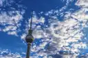 La torre de televisión de Berlín bajo un cielo azul con nubes
