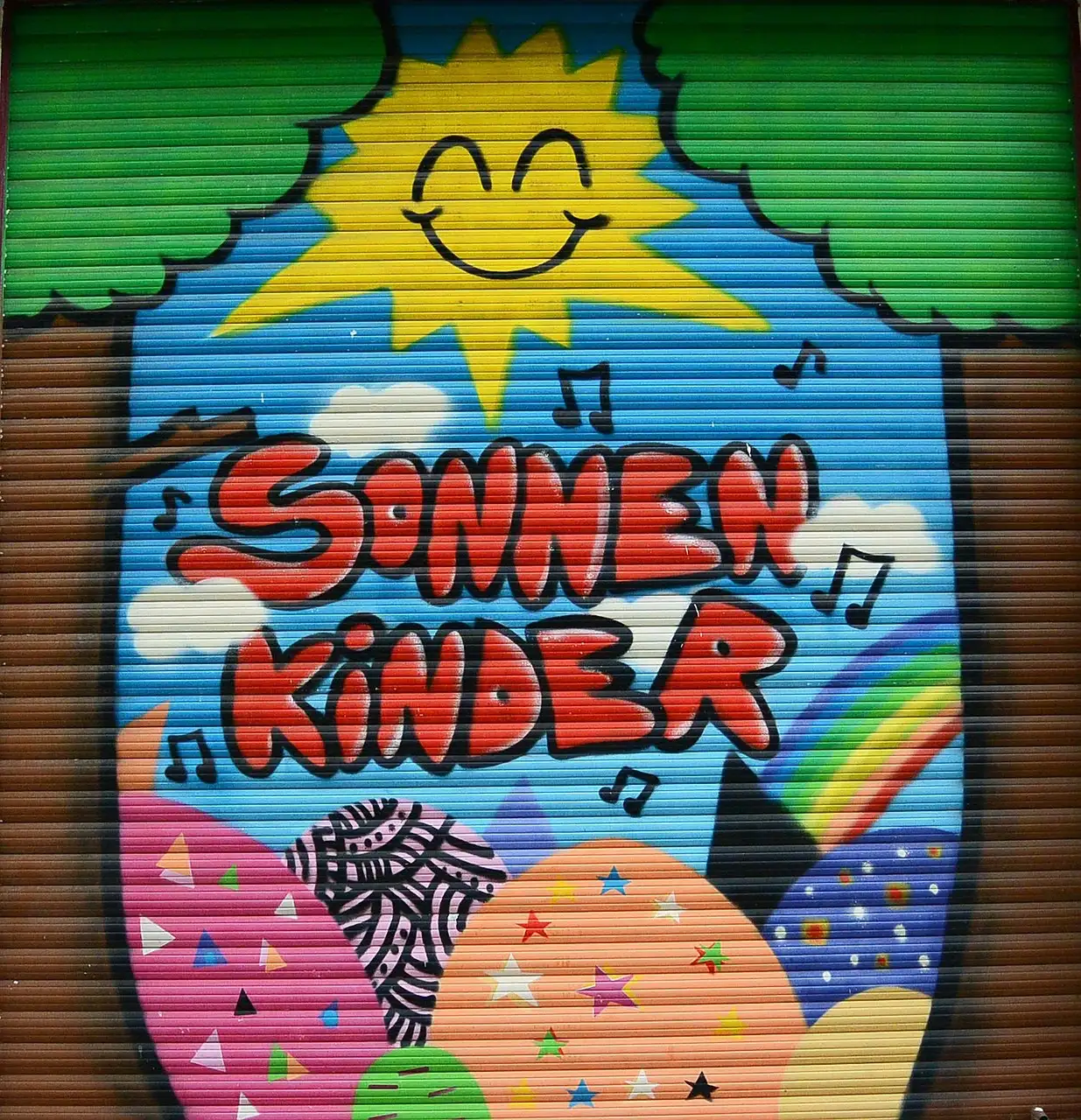 La persiana de una tienda pintada de colores, con un sol sonriente y las palabras Sonnen Kinder