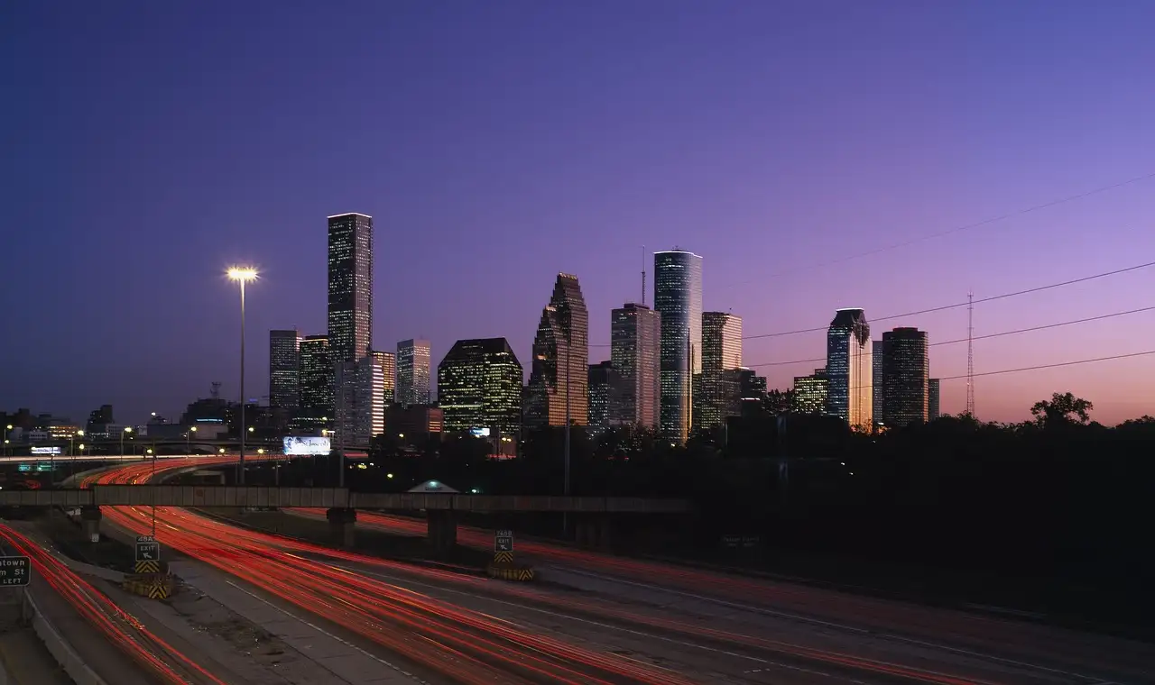 Las torres del centro de Houston al anochecer sobre una autopista con mucho tráfico