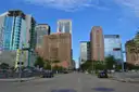 Una calle ancha del centro de Houston, flanqueada por torres de oficinas, bajo un cielo azul