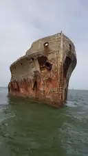 La proa oxidada de un viejo barco hundido que asoma del agua frente a Galveston