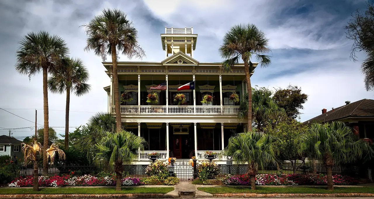 Una casa histórica con un porche amplio y palmeras en Galveston