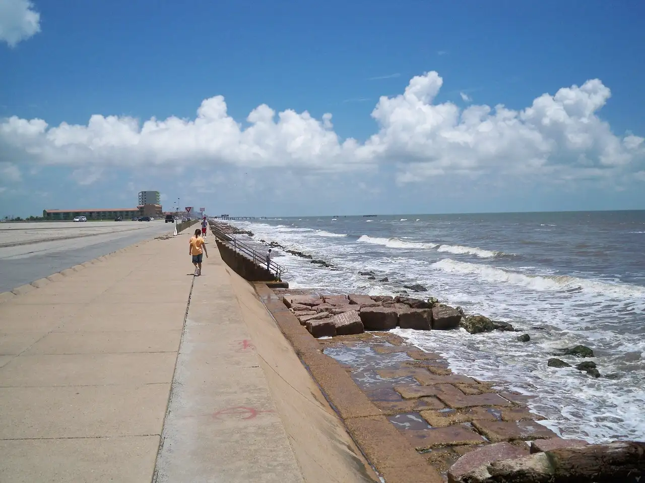 El paseo del malecón de Galveston junto al golfo de México, bajo un cielo azul con nubes