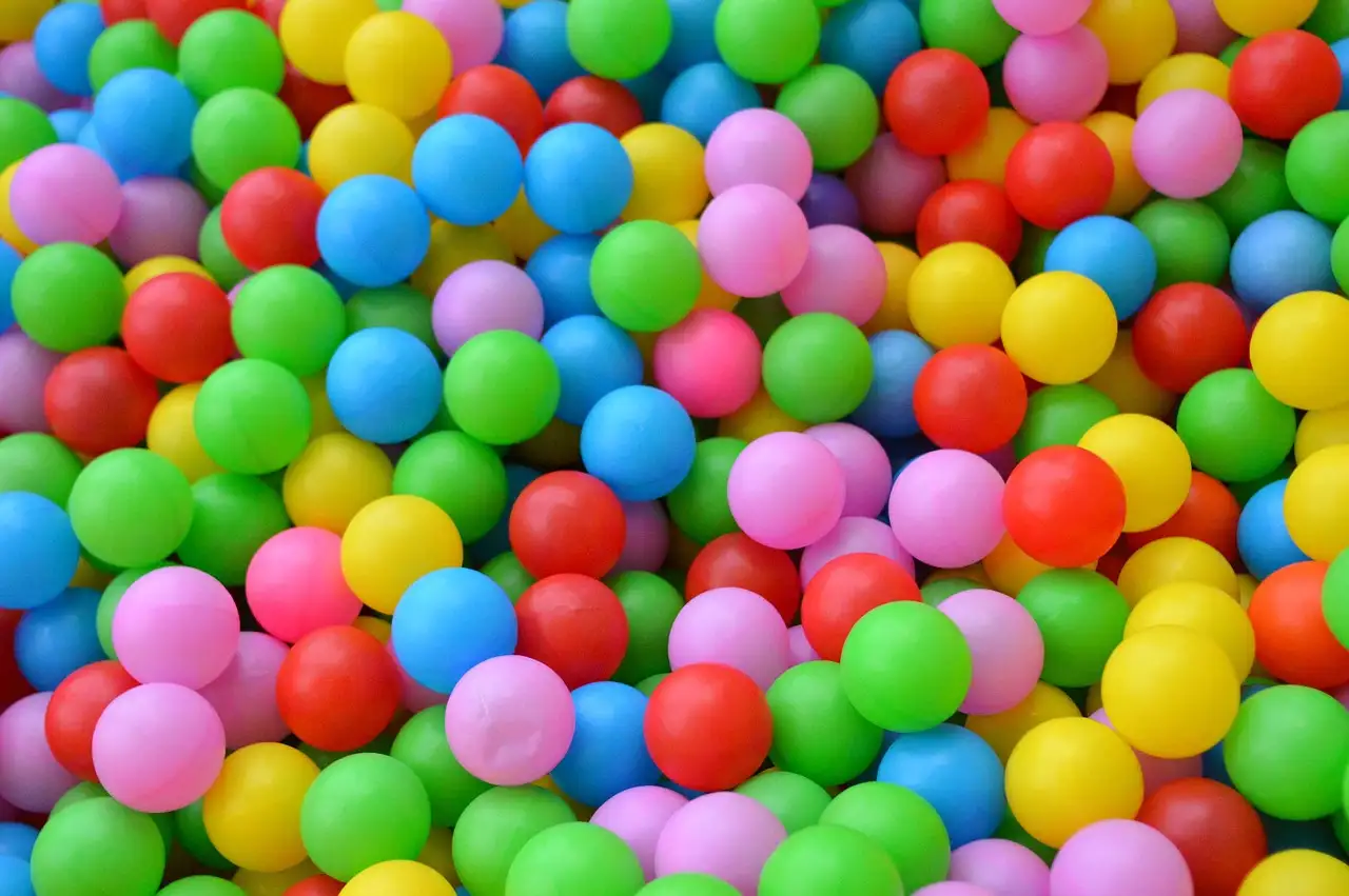 Una piscina de bolas llena de pelotas de plástico rosas, azules, verdes, amarillas y rojas