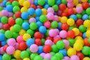 Una piscina de bolas llena de pelotas de plástico rosas, azules, verdes, amarillas y rojas