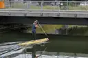 Una persona en una tabla de paddle surf pasa bajo un puente de la ciudad
