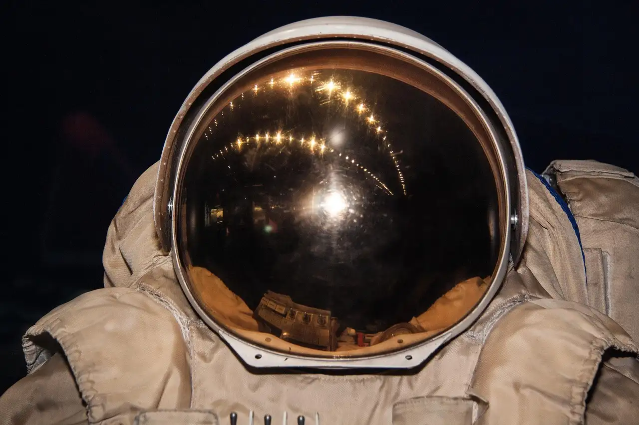 La visera dorada de un casco de astronauta sobre un traje espacial blanco, en primer plano