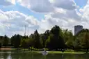 Una barca pequeña en el lago del Hermann Park de Houston, con árboles y un edificio alto detrás