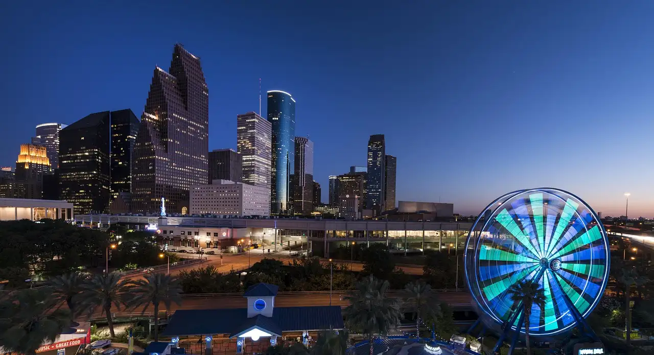 El skyline del centro de Houston iluminado al anochecer, con una noria iluminada delante
