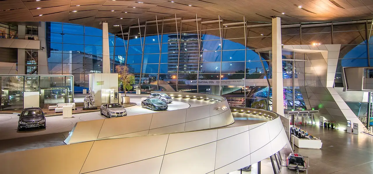 La sala de exposición luminosa y curva dentro de BMW Welt, con coches expuestos