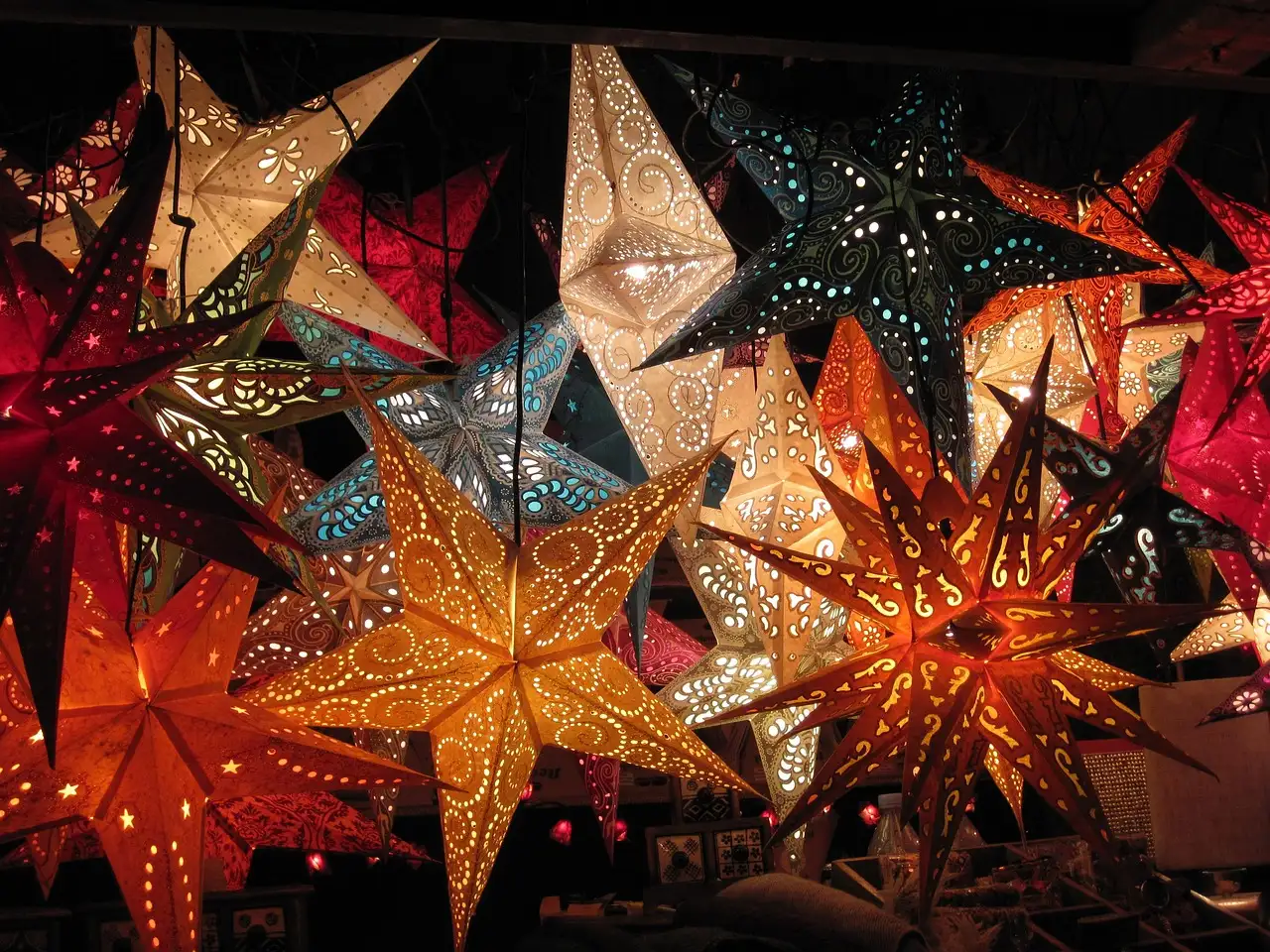 Farolillos de papel en forma de estrella, rojos, naranjas y blancos, en un puesto de mercado