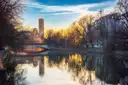 El río Isar en Múnich al atardecer, con un puente y una torre cuadrada alta en la otra orilla