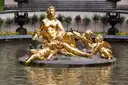 Un grupo de estatuas doradas en la fuente frente al Palacio de Linderhof