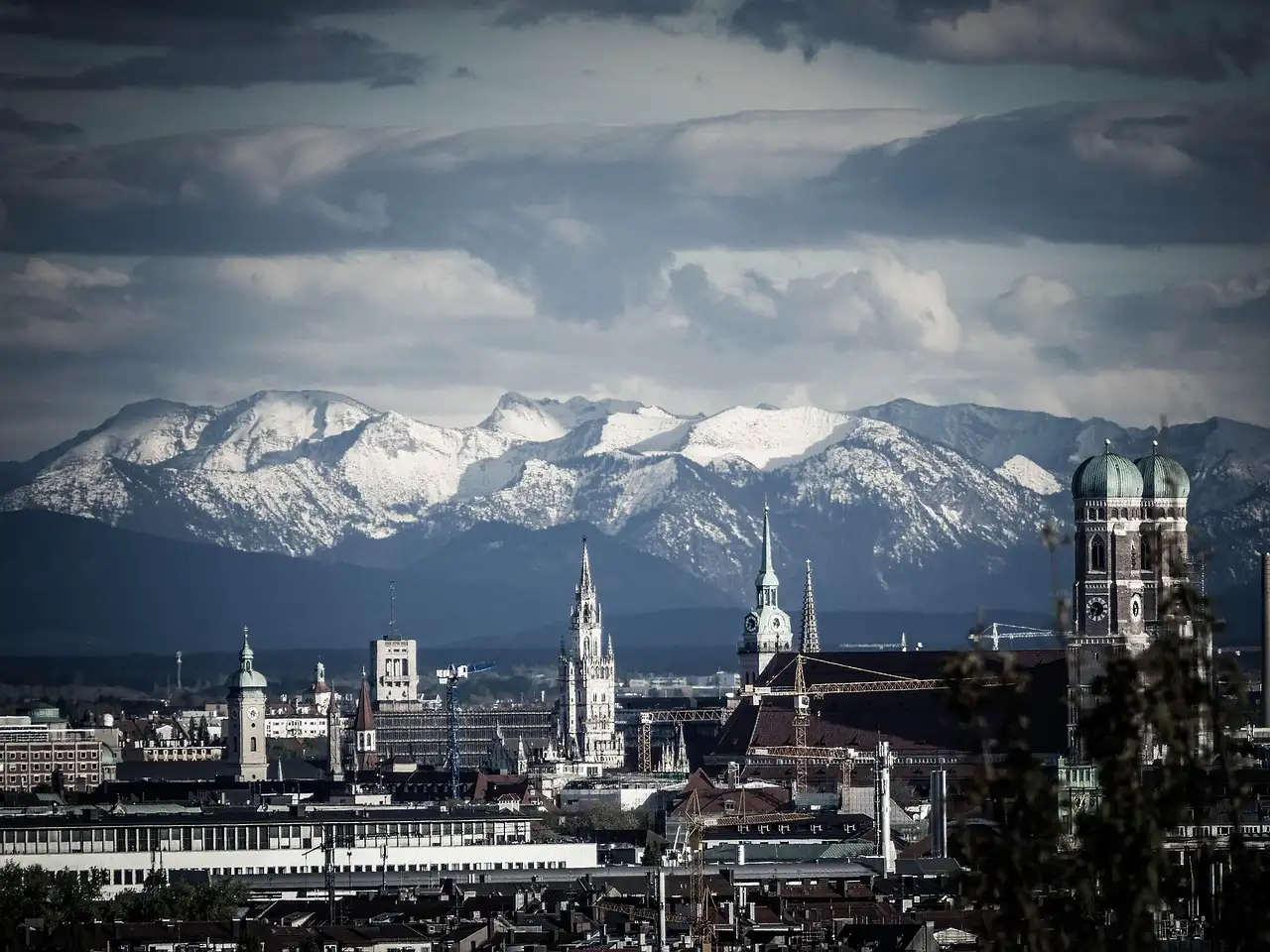 Las torres de la Frauenkirche y el casco antiguo de Múnich, con los Alpes nevados detrás bajo nubes oscuras