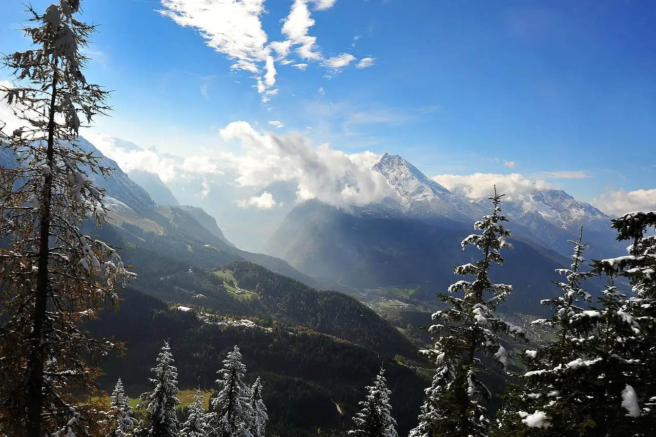 Vista sobre el valle de Berchtesgaden hacia cumbres alpinas nevadas, entre abetos cubiertos de nieve
