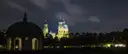 El templo redondo del Hofgarten de noche, con torres de iglesia iluminadas detrás