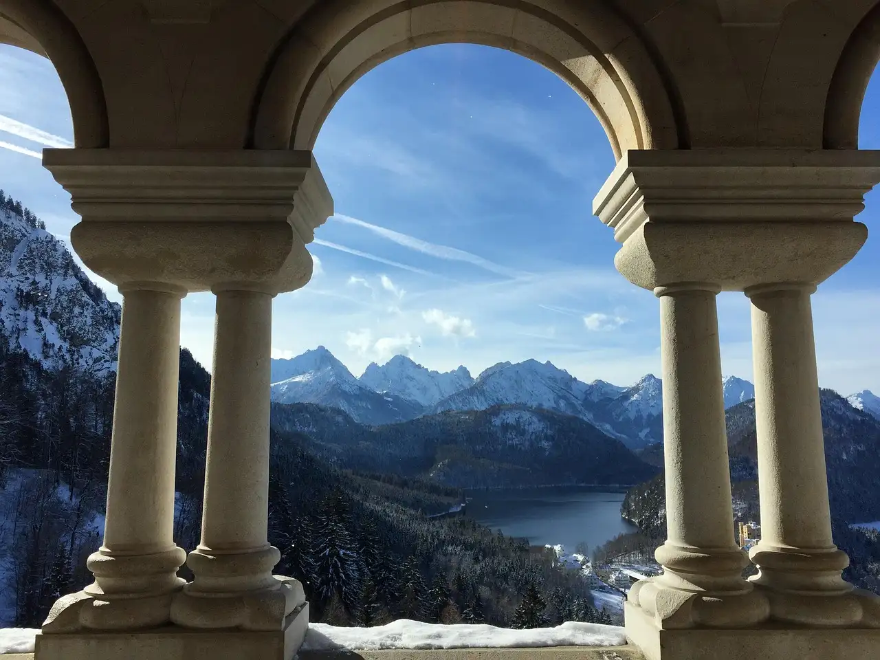 Un lago de montaña y picos nevados vistos a través de arcos de piedra