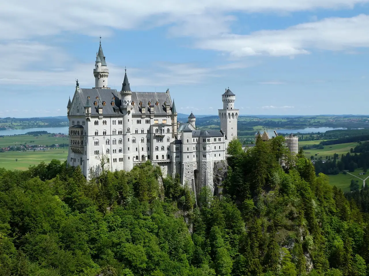 El castillo de Neuschwanstein sobre un bosque verde bajo un cielo azul