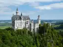 El castillo de Neuschwanstein sobre un bosque verde bajo un cielo azul