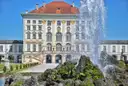 El edificio central del Palacio de Nymphenburg tras una fuente alta en un día de sol