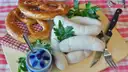 Salchichas blancas, un pretzel y mostaza dulce en una tabla de madera
