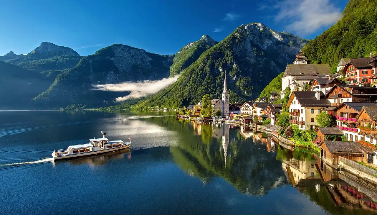 Las casas y la iglesia de Hallstatt a orillas de un lago de montaña en calma