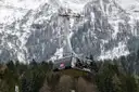 Una cabina de teleférico sobre un bosque nevado, con paredes de roca detrás