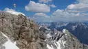 La cima rocosa del Zugspitze con su cruz dorada, bajo un cielo azul y con manchas de nieve
