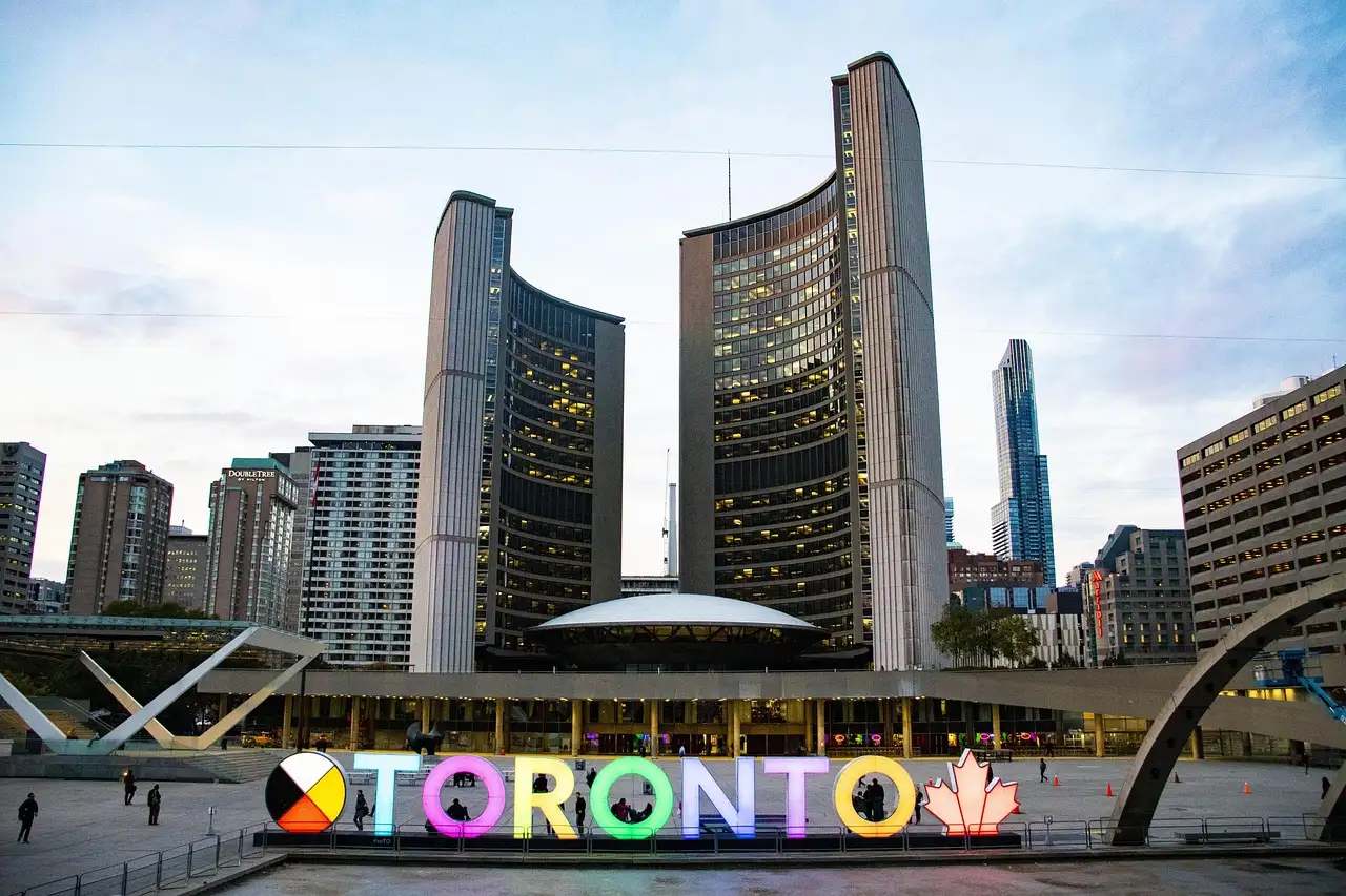 Las torres curvas del ayuntamiento de Toronto detrás del letrero TORONTO de colores en Nathan Phillips Square