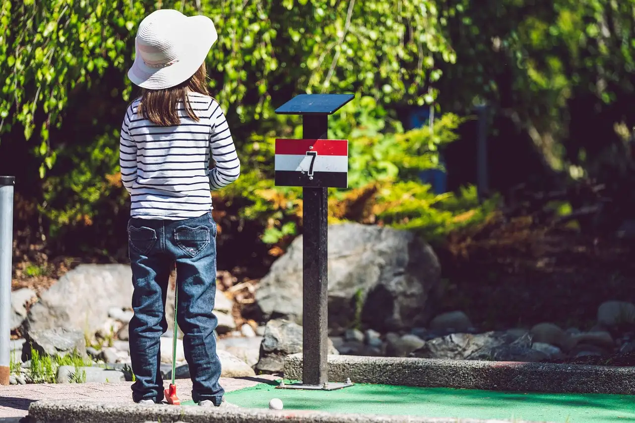 Un niño visto de espaldas en un minigolf