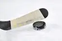 Un stick de hockey con cinta junto a un disco negro sobre el hielo blanco