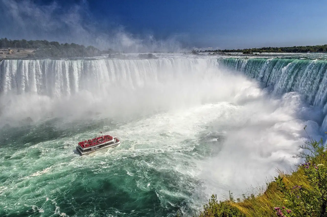 Un barco turístico rojo entre la bruma, al pie de las cataratas Horseshoe