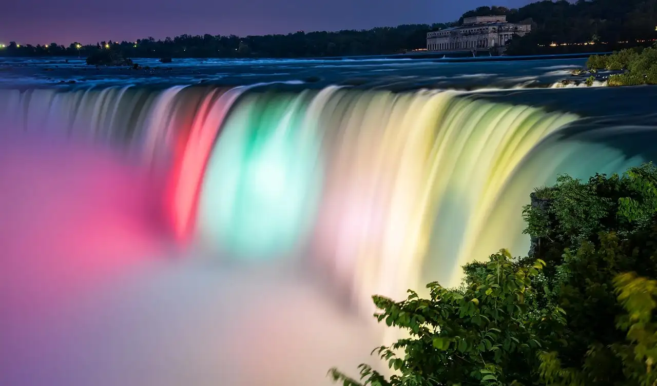 Las cataratas del Niágara iluminadas de noche en rosa, verde y amarillo