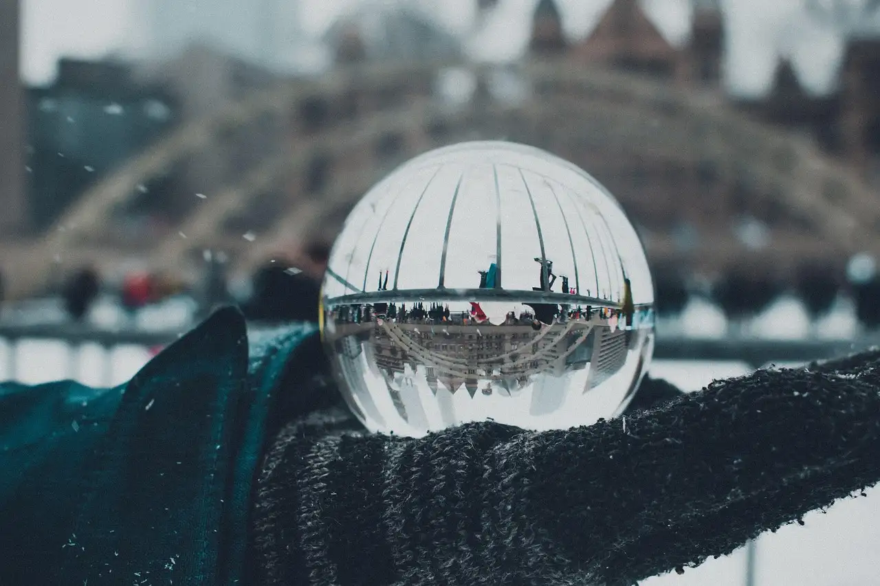 Una bola de cristal bajo la nieve en Nathan Phillips Square, con los arcos de la pista de patinaje detrás