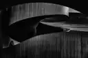 Las paredes curvas de madera oscura de una escalera de caracol dentro de una galería de arte de Toronto, en blanco y negro.