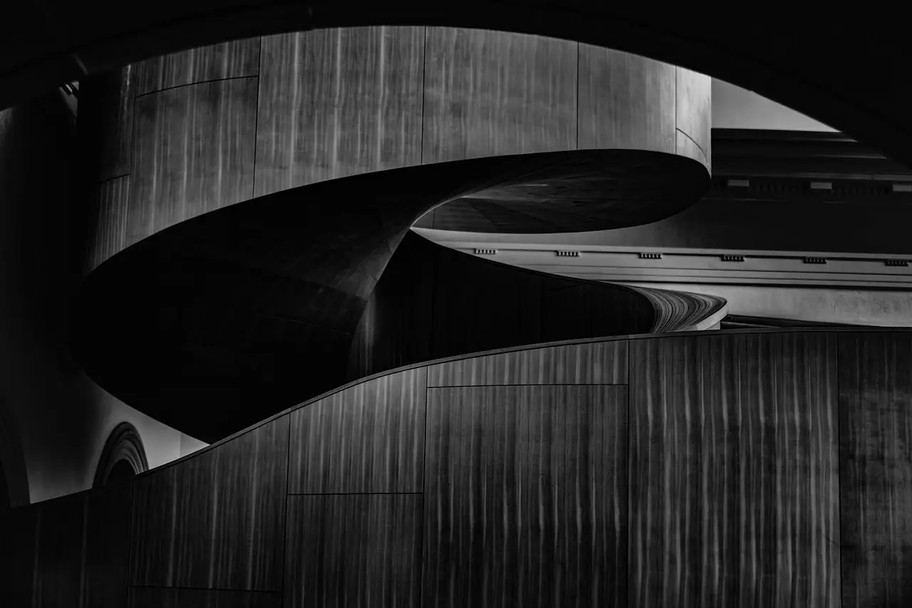 Paredes curvas de madera oscura en una escalera de caracol dentro de una galería de arte de Toronto, en blanco y negro.