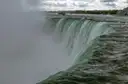 El agua cae por el borde de las cataratas Horseshoe hacia una nube de bruma, vista desde la orilla de al lado