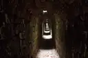 Un túnel de piedra estrecho con luz al fondo
